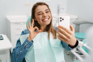 Smiling young woman in dental office after receiving Smile Design Dentistry treatment. 