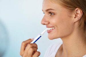 Woman using whitening pen as part of her teeth whitening treatment.